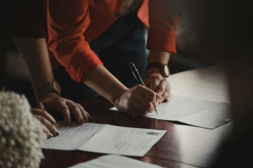 person in orange long sleeve shirt writing on white paper
